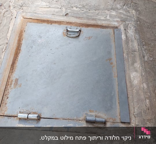 פתח מתכת מרובע עם ידית ובריחים על הקרקע